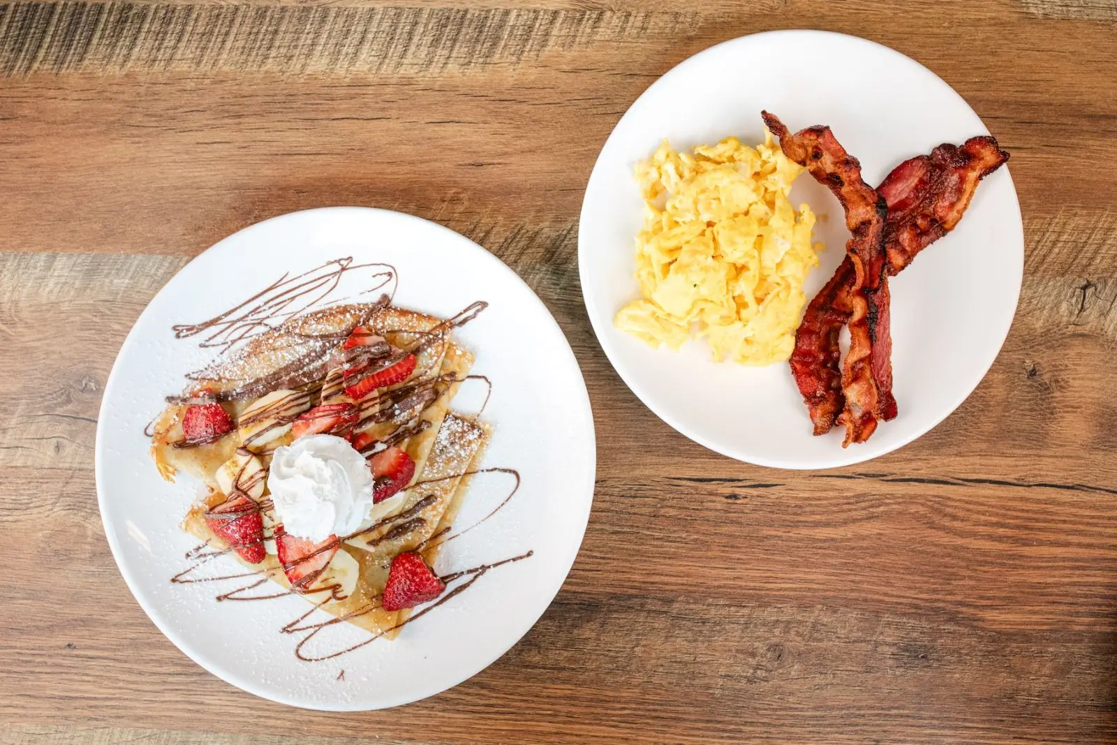 Strawberry banana crepes with chocolate drizzle, eggs and bacon