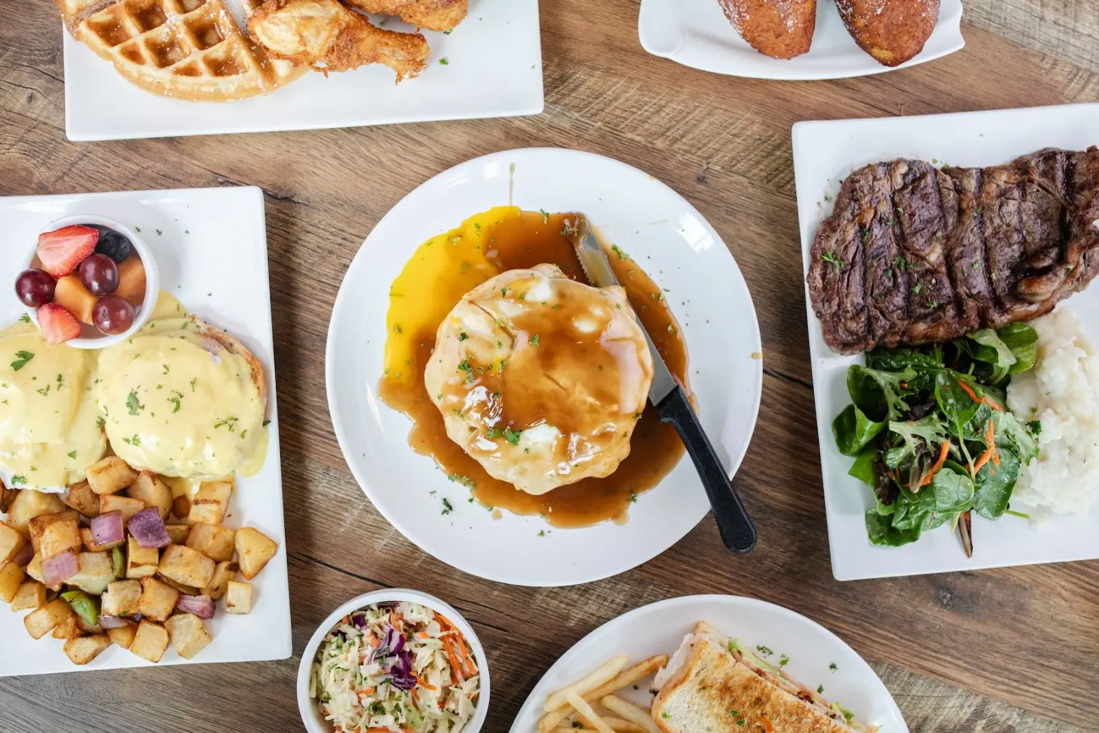 Diner spread — loco moco, eggs Benedict, rib eye, chicken and waffle