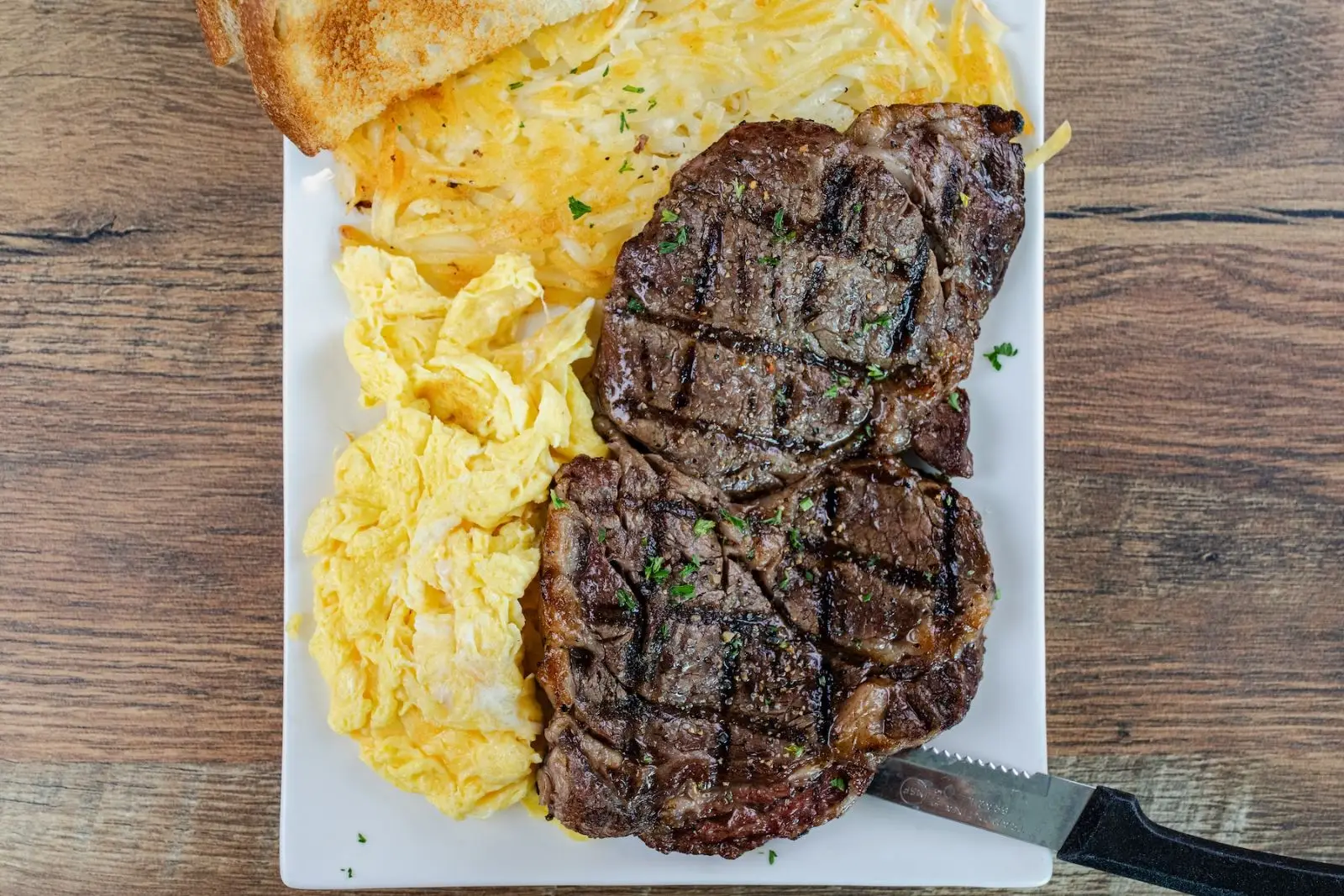 Rib eye steak with scrambled eggs and hash browns
