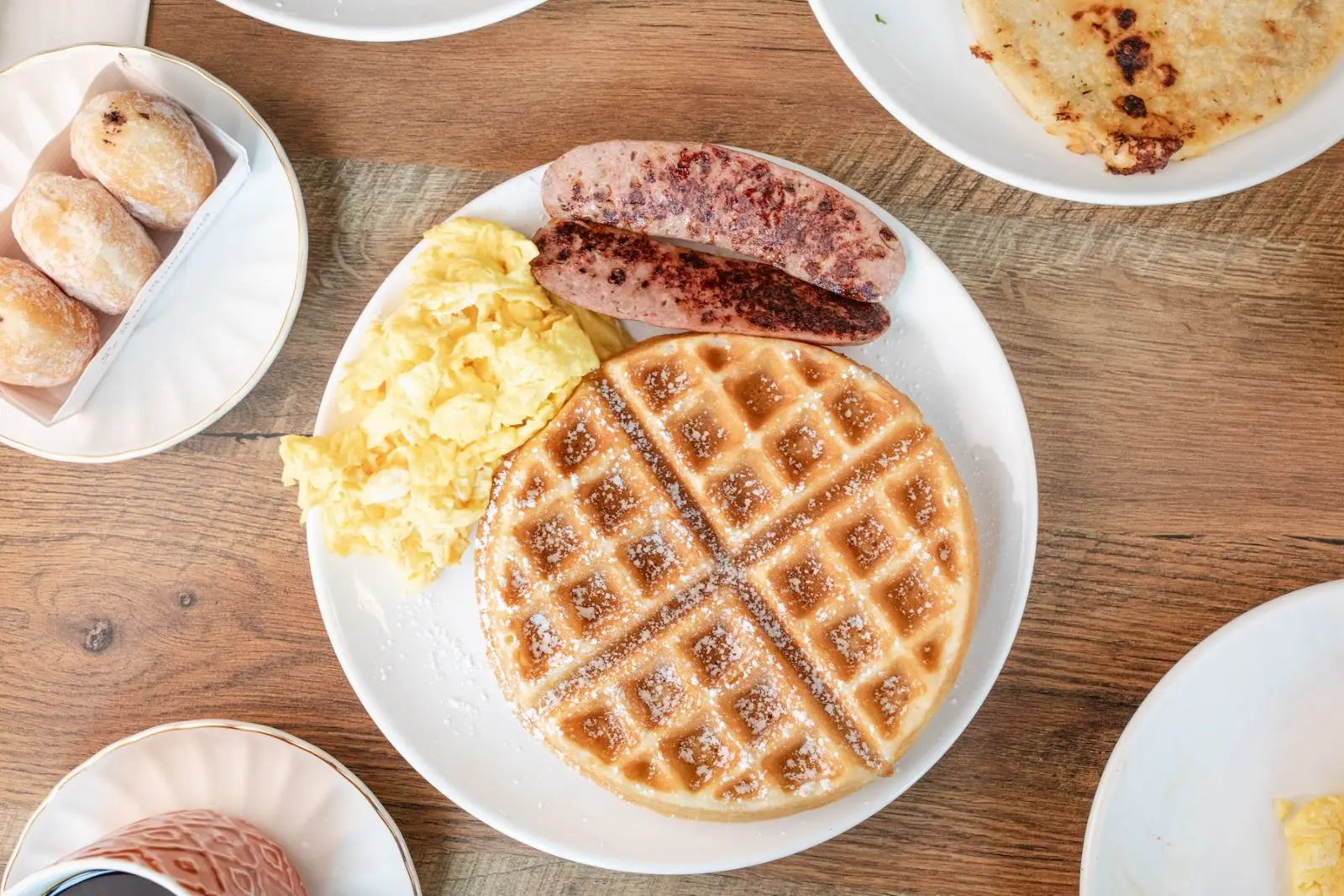 Waffle with eggs, sausage, donuts, and pupusa
